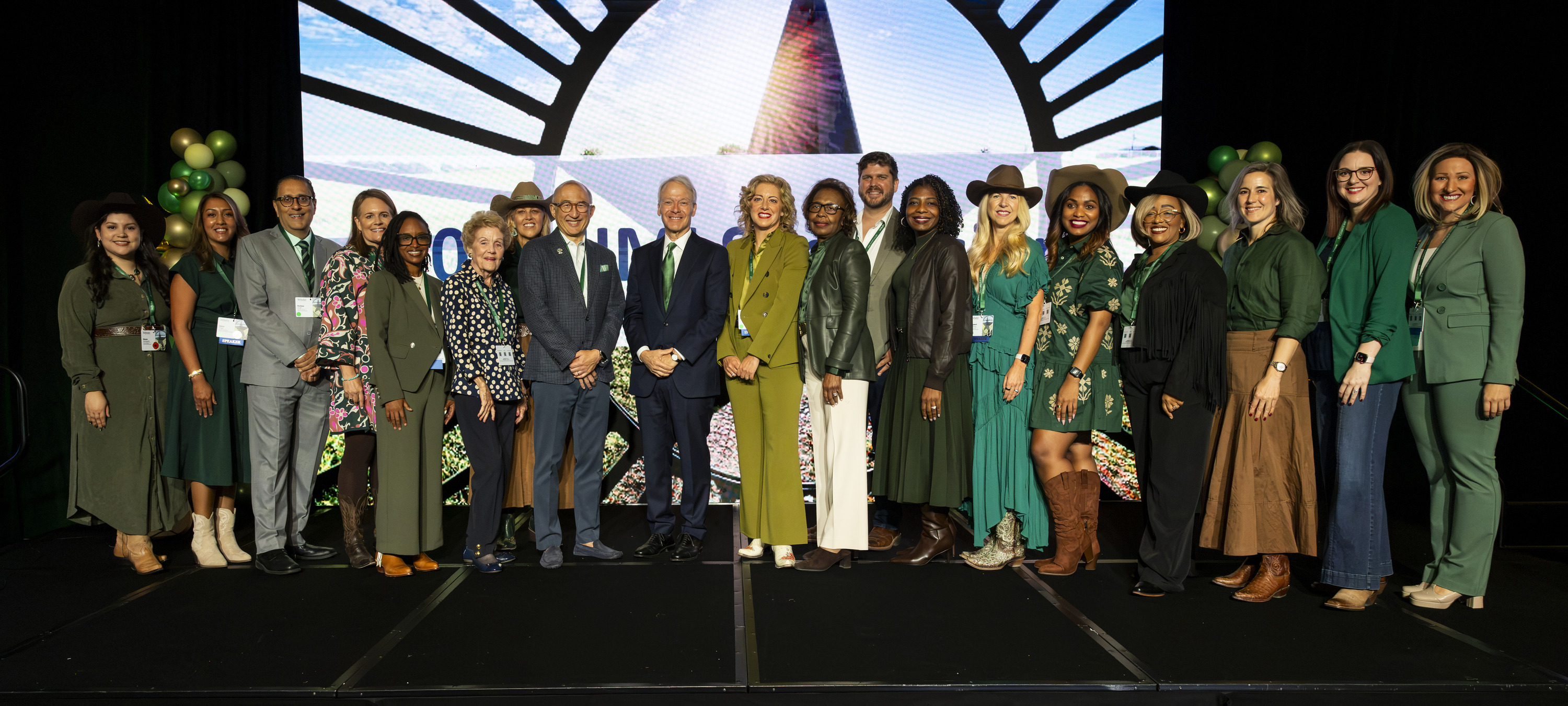 Group photo of 2026 JIMI Symposium participants standing together on stage